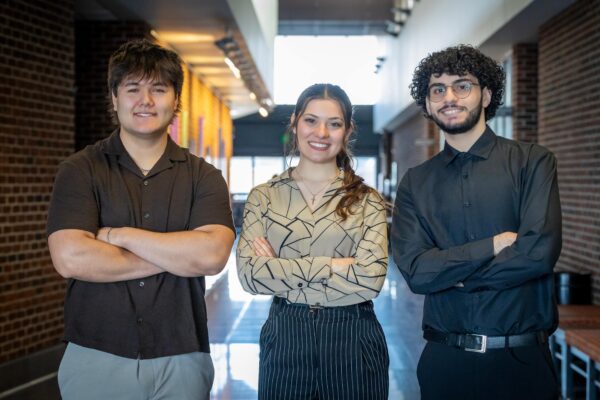 three students posing in hallway