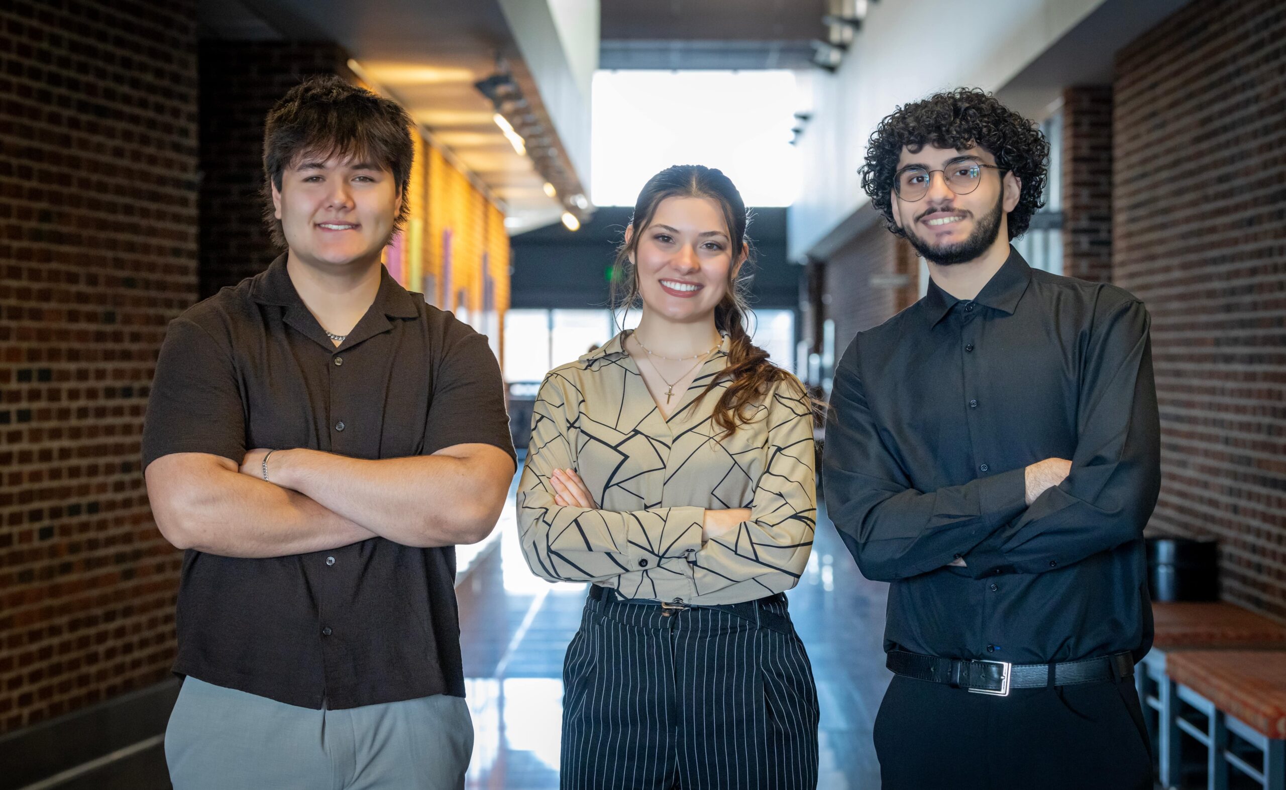 three students posing in hallway