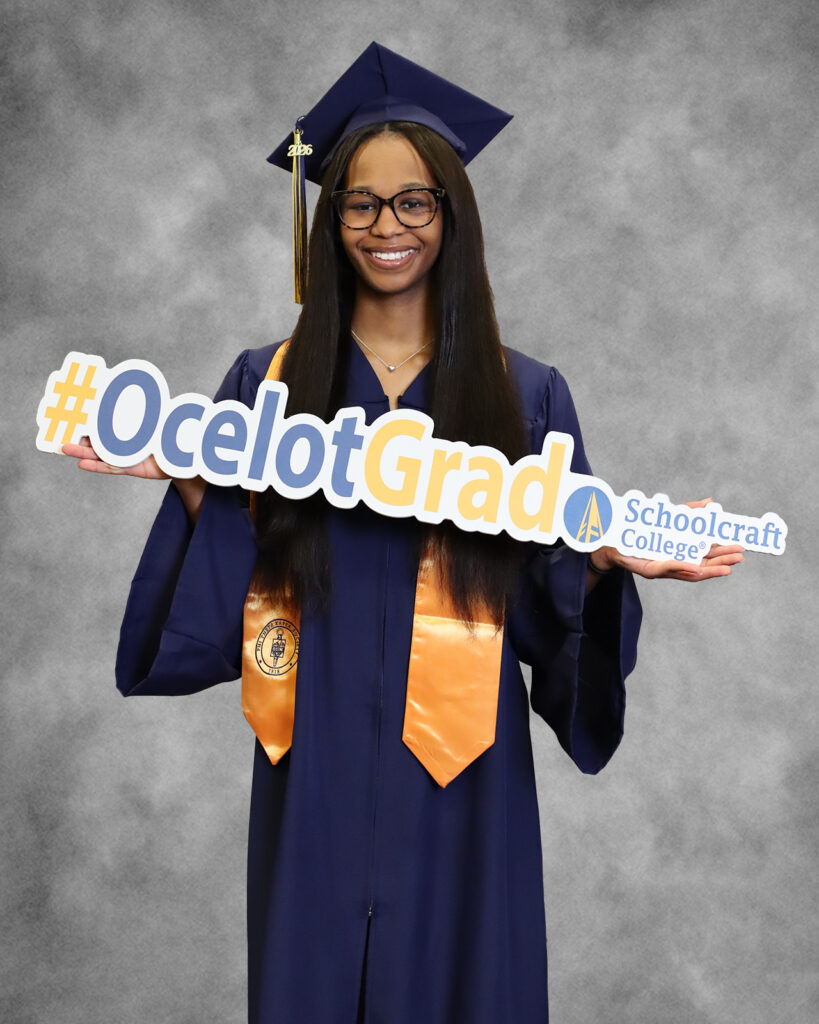 TereOnna Moore in regalia holding grad sign