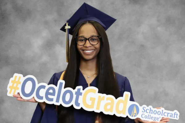 TereOnna Moore in regalia holding grad sign