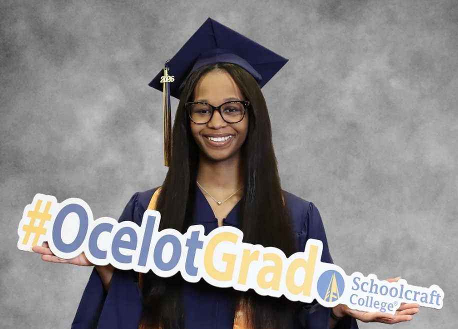 TereOnna Moore in regalia holding grad sign