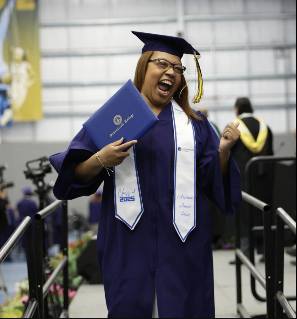 grad in regalia smiling with degree on stage
