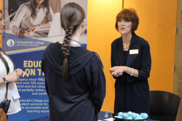 staff talking to prospective student at a table booth