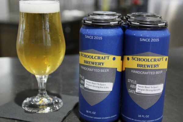 two beer cans next to a glass.