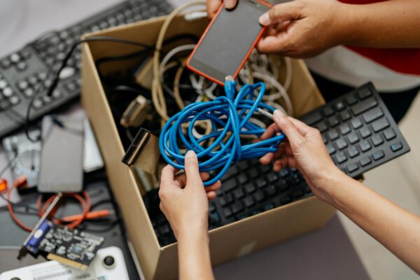 two people rummaging through a box of old electronics